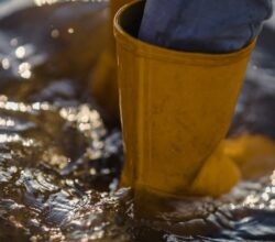 Image d'une personne portant des bottes et étant dans l'eau jusqu'aux chevilles