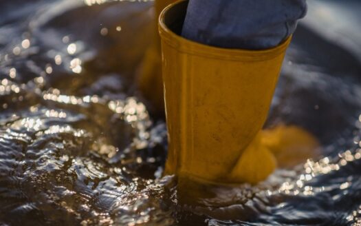 Image d'une personne portant des bottes et étant dans l'eau jusqu'aux chevilles